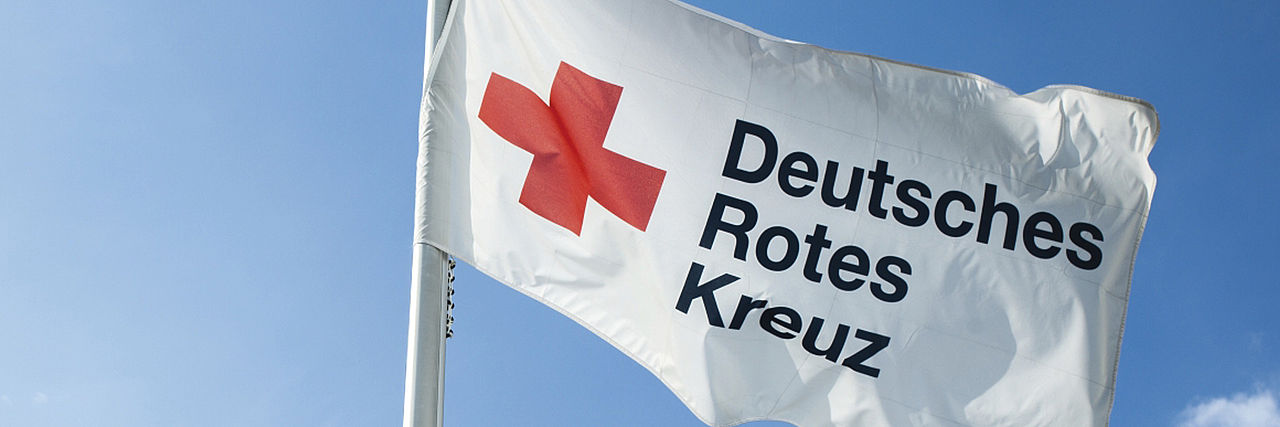 Handeln nach den Grundsätzen des DRK DRK-Flagge vor blauem Himmel